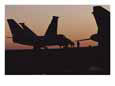 Silhouetted plane on an aircraft carrier at twilight.