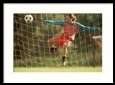 A Female Soccer Player Kicks the Ball Near the Goalpost