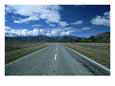 Straight Road Heading Towards Mountains and Clouds