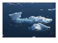 An aerial view of an iceberg and small floating chunks of ice