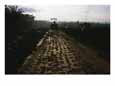 A roller flattens a muddy dirt road