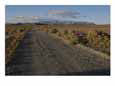 A dirt road leads toward the distant hills