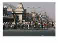 Crowds on Bikes Fill a Street Near a Bazaar and Hindu Temple