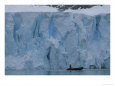 A Zodiac boat under the calving ice front of Rudolf Glacier.