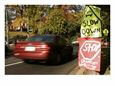 Car Racing Past Hand-Made Signs Imploring Drivers to Slow Down Scenic Streets & Roadways