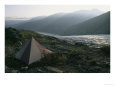 A mountain campsite with a tent set up near a glacier.