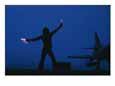 A Ground Control Person Guides a Plane on an Aircraft Carrier